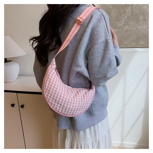 Rear view of a model wearing a pink and white checkered crescent crossbody bag indoors