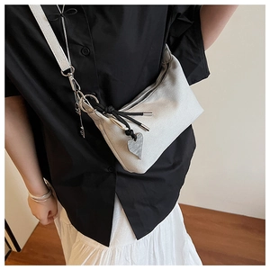 Detail of silver gray fabric shoulder bag with heart pendant and woven knot tassel