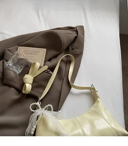 Detail of cream leather shoulder bag featuring lace edges and adjustable pearl strap
