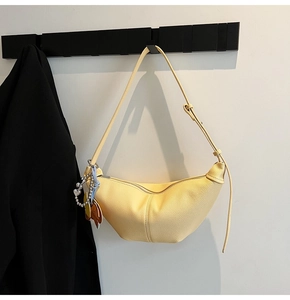 Close-up of yellow pleated hobo bag with pebble leather texture and cute charm detail