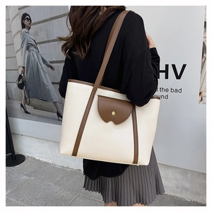 Detail of the cream tote bag showing lychee grain texture and brown decorative straps