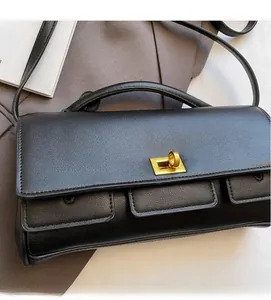 Detail shot of black textured leather handbag with elegant golden rectangular twist lock
