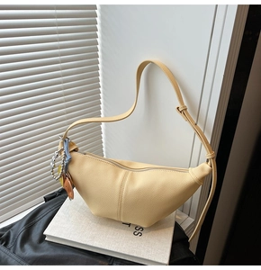 Close-up of a pale yellow pleated croissant bag with litchi grain texture and strap