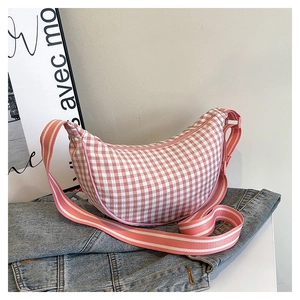 Detail of pink and white checkered crescent crossbody bag with striped adjustable strap