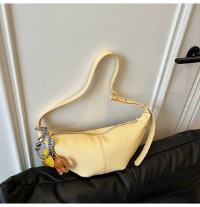Macro detail of yellow textured leather crescent bag with colorful elephant charm