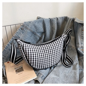 Detail of gingham crescent crossbody bag with striped strap on casual denim jacket