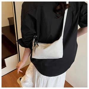 Rear view of model wearing minimalist white pillow crossbody bag with heart pendant charm