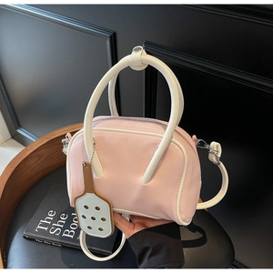 Close-up of pink and white contrast handbag with unique tennis racket charm on a chair