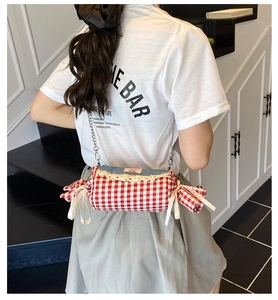 Detail of candy-shaped crossbody bag with red gingham and blue denim on a model
