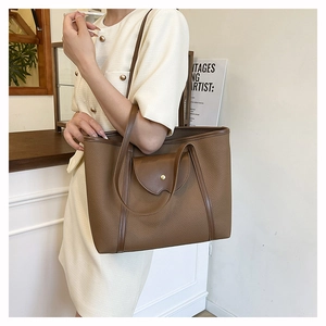 Close-up of brown vintage tote bag with wave-edge flap pocket and gold metal buckle