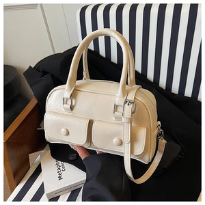 Detail of a creamy beige leather Boston bag with decorative front pockets and dual handles
