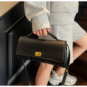Detail of black matte square bag with gold metal twist lock and pleated bottom texture
