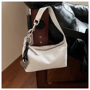 Detail of white matte shoulder bag featuring a bold silver chain and heart charm