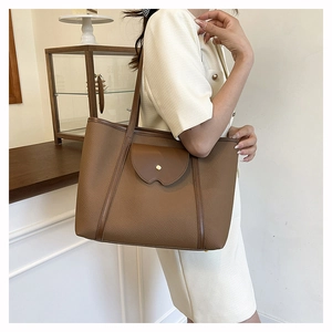 Detailed shot of large brown pebbled leather tote bag with front flap and gold studs