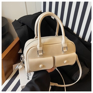 Detail view of cream Boston handbag featuring front flap pockets and adjustable strap