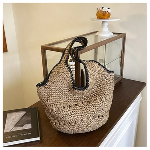 Détail d'un sac cabas en paille tissé à la main avec bordure noire et motif ajouré