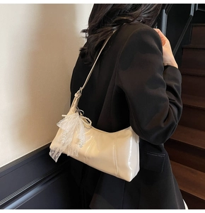 Detail of cream white half-moon bag with delicate lace bow and pearl charm accents