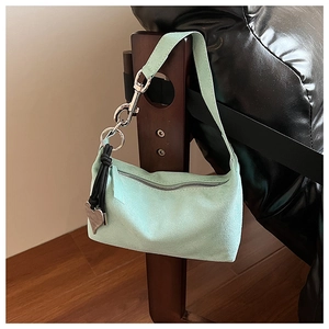 Detail of mint green suede shoulder bag with metallic chain and heart charm