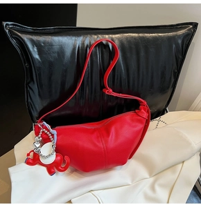 Detail of red lychee grain leather hobo bag with elephant charm and silver heart chain