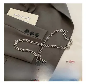 Detail of silver alloy chain strap on blue denim handbag with red and white checkered trim