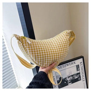 Detailed close-up of yellow and white checkered crescent crossbody bag with striped strap