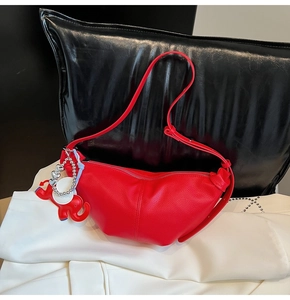 Detail of red crescent bag with lychee texture leather and cute elephant charm accessory
