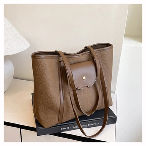 Close-up of brown litchi pattern leather tote bag with golden buckle pocket detail