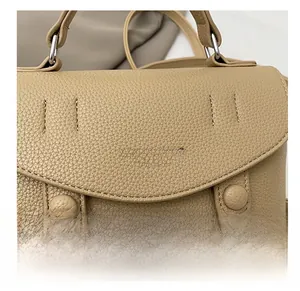 Detail of khaki leather handbag featuring lychee texture and fashion printed lettering