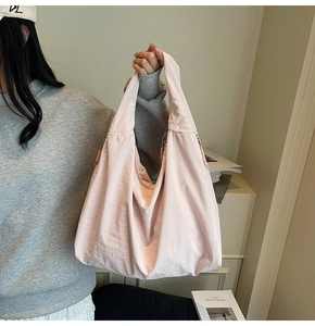 Detail view of large light pink tote bag showing texture and side zipper on a model