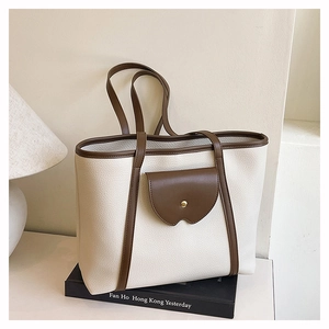 Close-up of litchi grain cream leather tote bag with brown contrast trim and metal snap