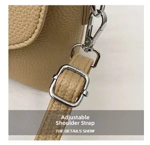 Detail of beige lychee leather bag showing silver metal buckle and adjustable strap