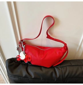 Macro shot of red leather crescent bag with textured finish and cute elephant charm