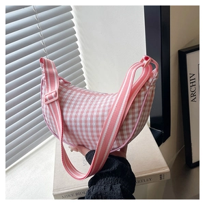 Pink checkered dumpling bag with adjustable strap shown in a stylish lifestyle setting