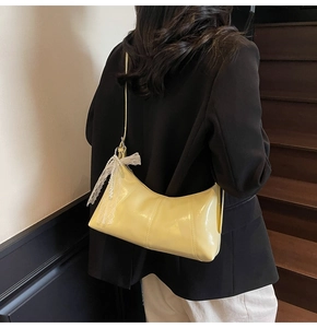 Rear view of a yellow patent leather hobo bag featuring lace bows and pearl charms