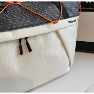 Detail of grey checkered fabric and white textured canvas with orange elastic drawstring