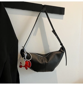 Detail view of black leather hobo bag with a cute elephant pendant on a metal hook