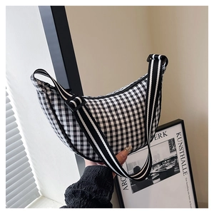 Detailed shot of black and white gingham crescent bag with striped nylon shoulder strap