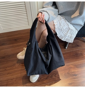 Detail of large black hobo tote bag with silver zipper and subtle fabric texture