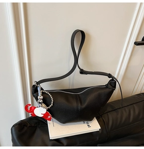 Detail of black crescent moon bag featuring pebbled leather texture and elephant charm