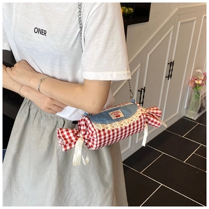 Detail of candy-shaped checkered handbag with blue denim flap and lace trim on model