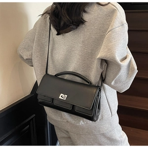 Detail of the black leather baguette bag on a model showing size and drape effect