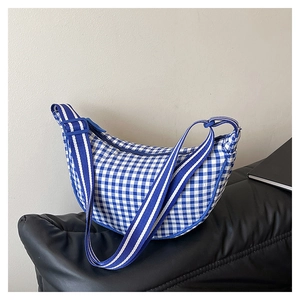 Detailed shot of blue and white checkered crescent bag with adjustable striped strap
