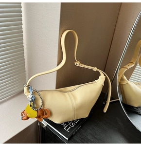 Detail view of light yellow crescent bag with litchi texture and cute animal charms