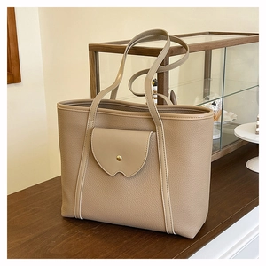 Detailed close-up of khaki pebbled leather tote bag with unique front flap pocket design