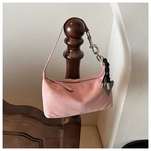 Pink suede pillow bag detail with silver zipper and metallic heart pendant accessory