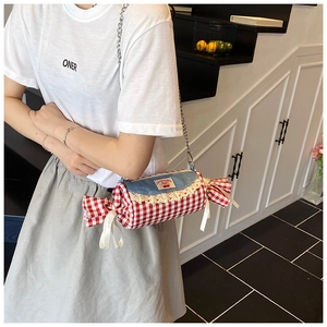 Chic candy-shaped crossbody bag featuring red checkers and lace trim on a female model