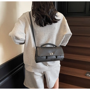 Classic black baguette bag with metal twist-lock and shoulder strap shown on model