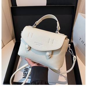 Detail of off-white lychee texture leather bag inside a premium black gift box packaging