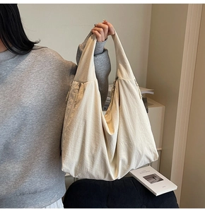 Close-up detail of a cream-colored tote bag showing double zippers and fabric texture
