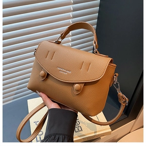Detail of brown litchi pattern leather handbag featuring round buckle and white logo